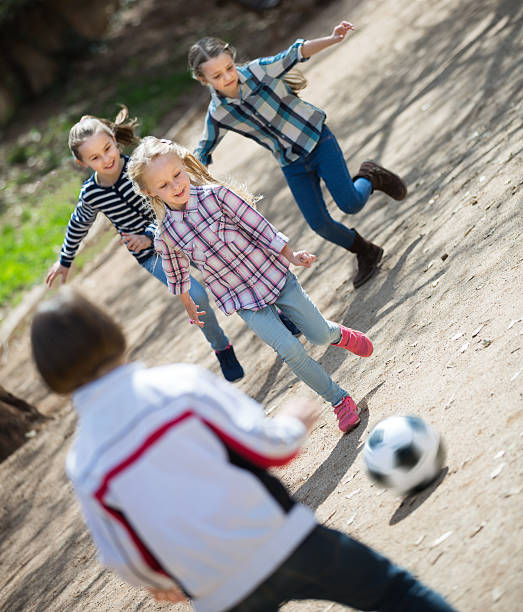 bambini amichevoli che giocano a calcio di strada all'aperto - football player group of people running american football foto e immagini stock