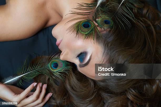 Beautiful Woman Lying On Bed With Peacock Feather And Makeup Stock Photo - Download Image Now