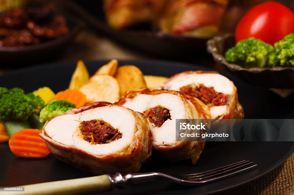 Delicious chicken rolls with dried tomatoes and mozzarella. Delicious chicken rolls with dried tomatoes and mozzarella, served with vegetables and roasted potatoes. Appetizer Stock Photo