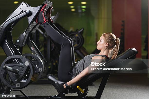 Sportive Woman Using Weights Press Machine For Legs Gym Stock Photo - Download Image Now