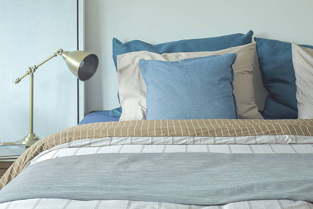 istock Blue and beige pillows on bed and chrome reading lamp 596096678