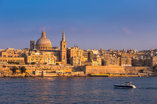 Valletta, Malta - Motorboat and the famous St.Paul's Cathedral with the ancient city of Valletta at sunset