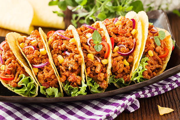 istock Tacos with meat and vegetables on wooden board 596337270
