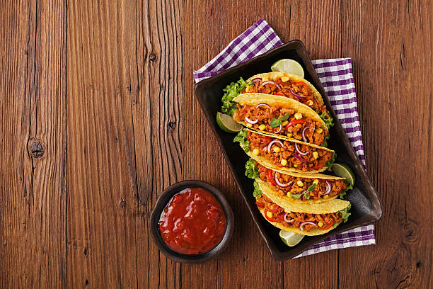 istock Tacos with meat and vegetables on wooden board 596338630