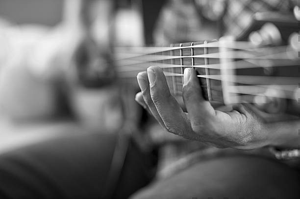 istock playing acoustic guitar, barre chord,selective focus,black and w 596340938