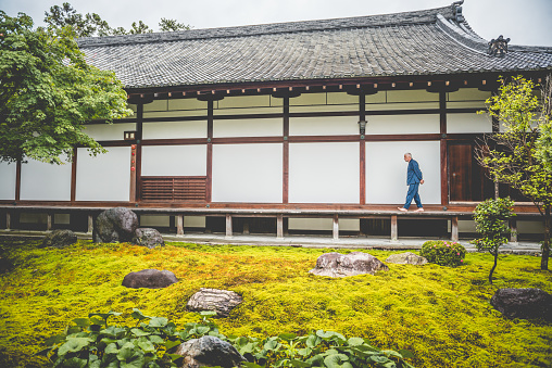 Senior Caucasian man meditating in Chionji Temple in Kyoto City, Japan, Asia. He is walking on the wooden patio and looking at a beautful garden. One man only, full lenght, side view. Nikon D800, full frame, XXXL. iStockaLypse Kyoto 2016.