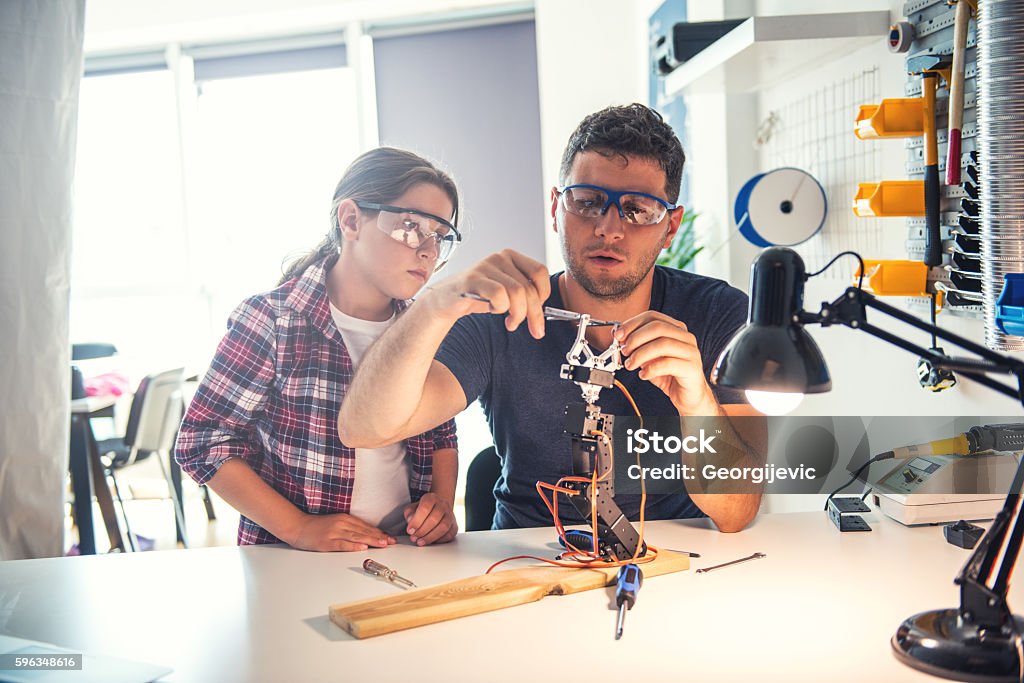 Learning from teacher Student and teacher working on a robotic arm in a classroom. Robot Stock Photo