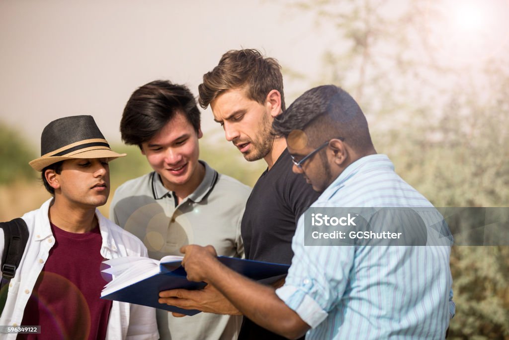 Senior college student explaining freshmen about new syllabus. University Graduate Student being asked for some help by some Freshmen Students. Variation Stock Photo