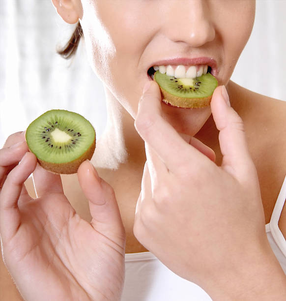 istock happy smiling woman bite a kiwi 596349558