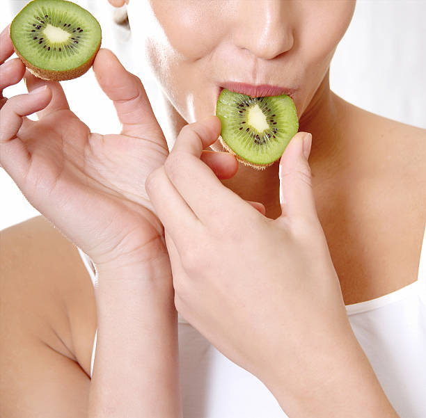 istock happy smiling woman bite a kiwi 596349686