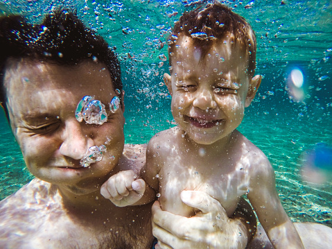 Daddy and son having fun underwater in the sea,