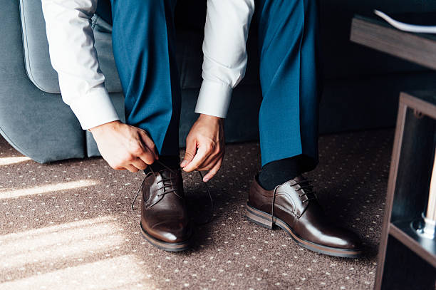 istock Close-up young man tying elegant shoes indoors 596351182