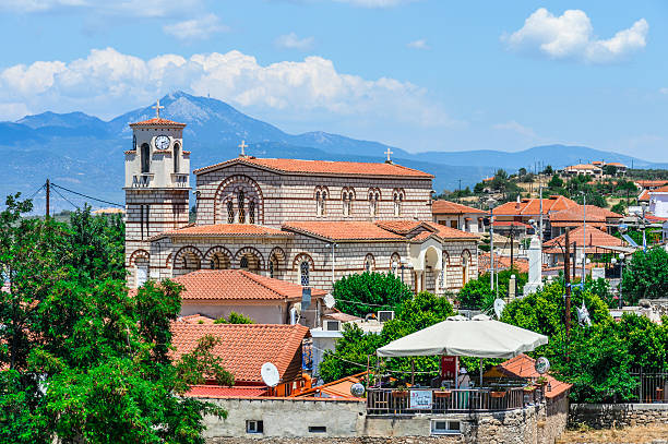 Ancient Corinth, Greece - June 11, 2016: Greek village near the ruins of Ancient Corinth. Photo taken during a summer day and contains a church, some cafes, and some people.