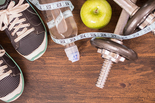 istock Fitness, exercise themed scene with barbells, sneakers, apple. 596359212