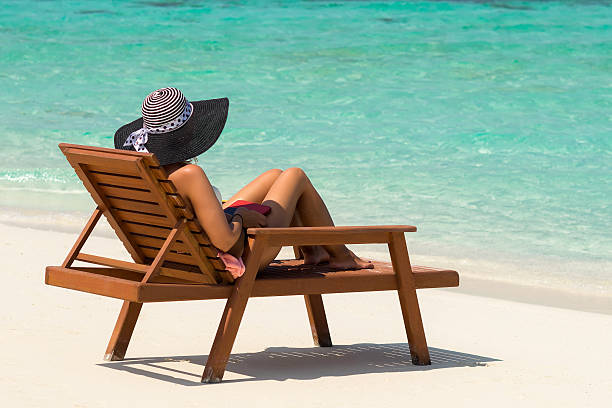 istock Young woman sunbathing on lounger at tropical beach 596359420