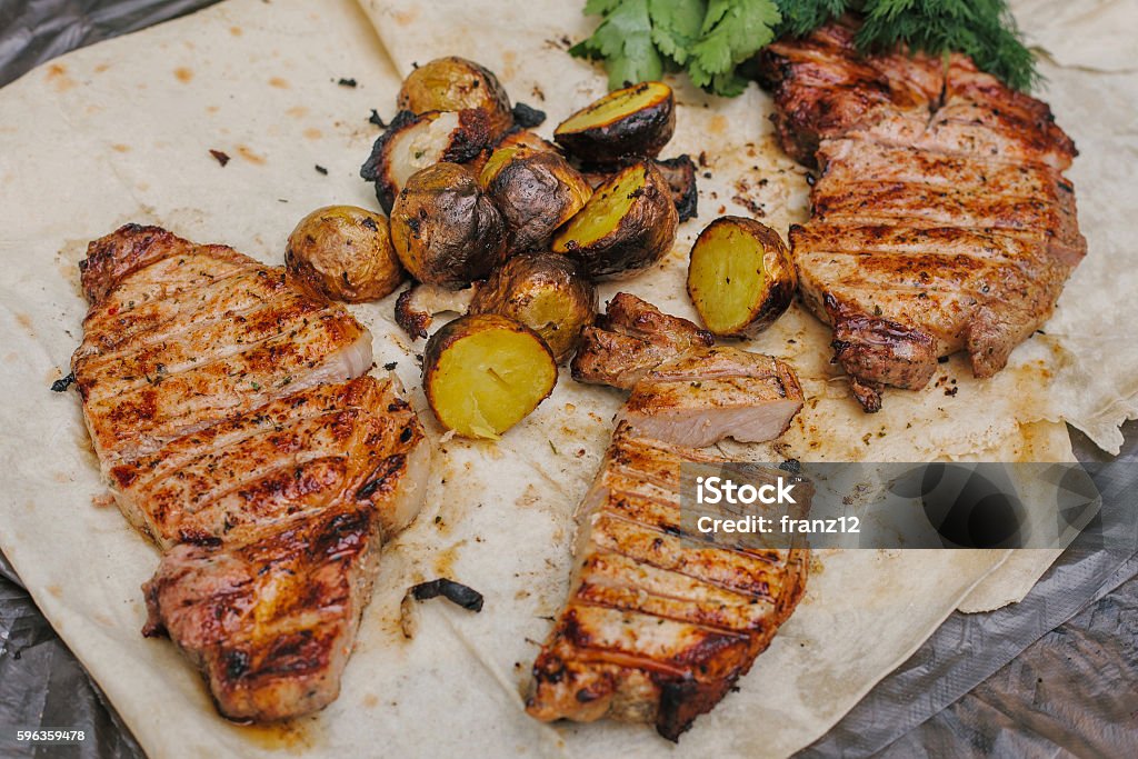 Grilled steak, bacon and potatoes lies in the pita. Grilled steak, bacon and potatoes with herbs lies in the pita. The concept of eating outdoors in the weekend. Appetizer Stock Photo