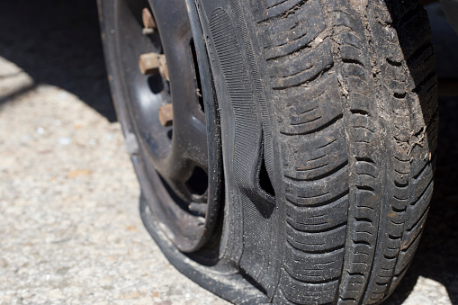 Flatten car tyre close up. Visible puncture. Photo is taken with dslr camera.