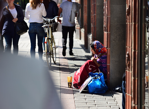 Stockholm, Sweden - August 22, 2016: Romanian beggar on the streets of Stockholm. Sitting down on sidewalk outside shop.  A new but common scene outside shops in most cities in Sweden..