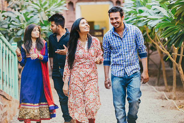 In Jodhpur, India, four happy young Indian friends are walking together. The women are wearing traditional clothes.
