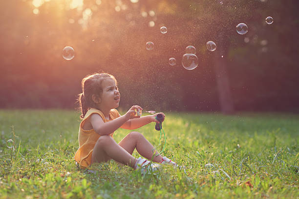 istock Little girl playing with soap balloons 596366660