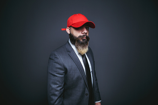 young bearded man with a hat in front of a light glass wall