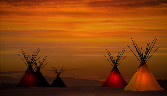 Teepee prairie camp and gold, dark,  sunset- light in teepees- copy space