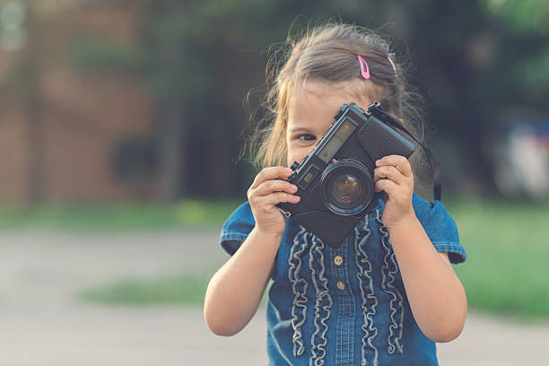 istock Little girl playting with old camera 596369378