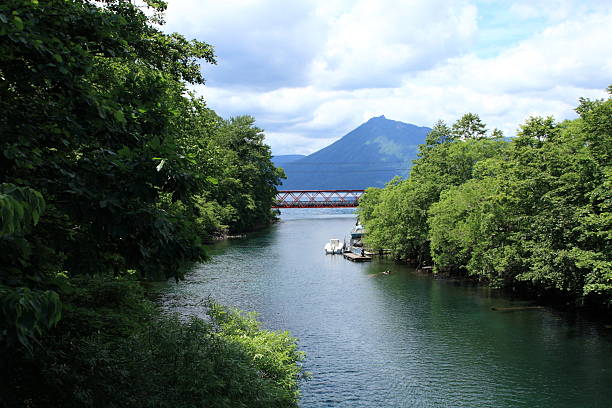 mountain and river with a red iron bridge stock photo