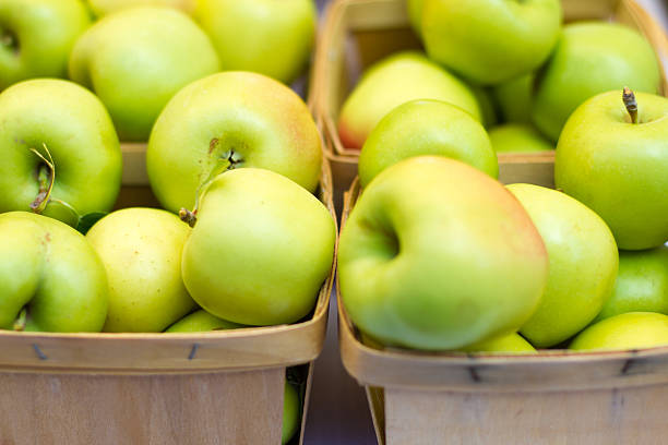 Homemade rustic green apples in a basket on an old stool. Selective focus.