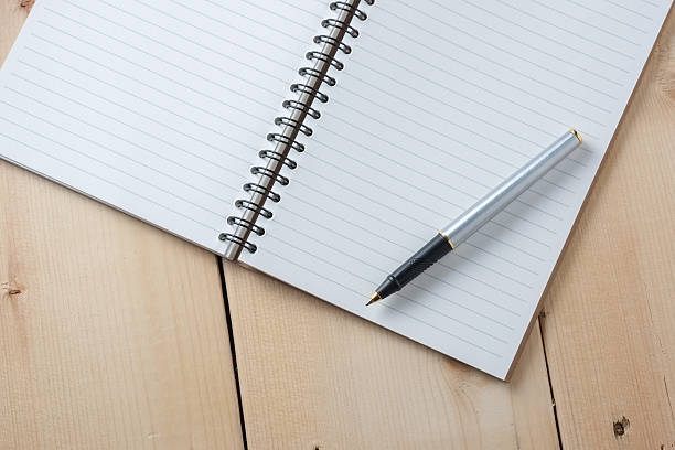 istock pen and book on wood background 596376430