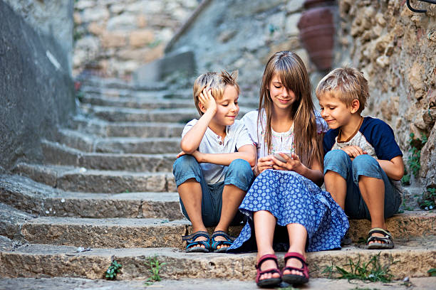 istock Kids using smartphone on an old weathered stairs 596379104