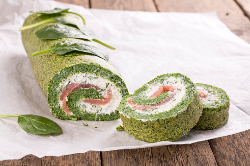 Green spinach roll with soft cheese and salmon
