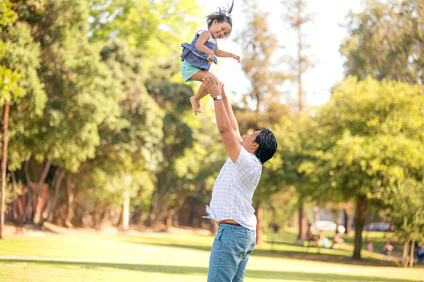 istock Young ethnic father tossing his daughter in the air 596385098