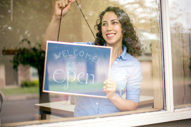 istock Young female business owner hanging open sign 596385282