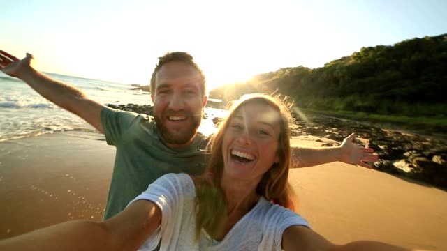 Cheerful young couple on the beach take a selfie portrait