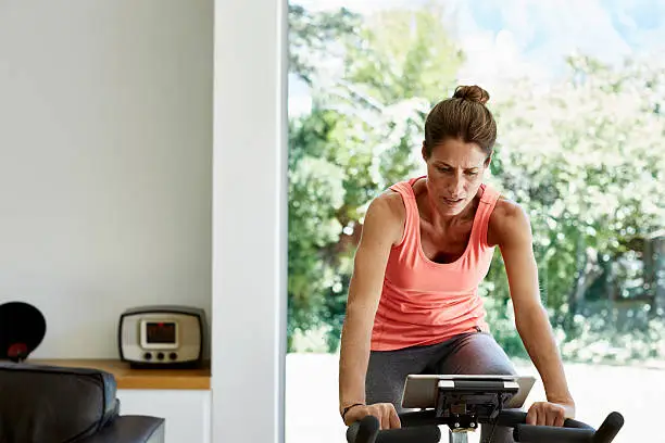 Woman working out on exercise bike at home