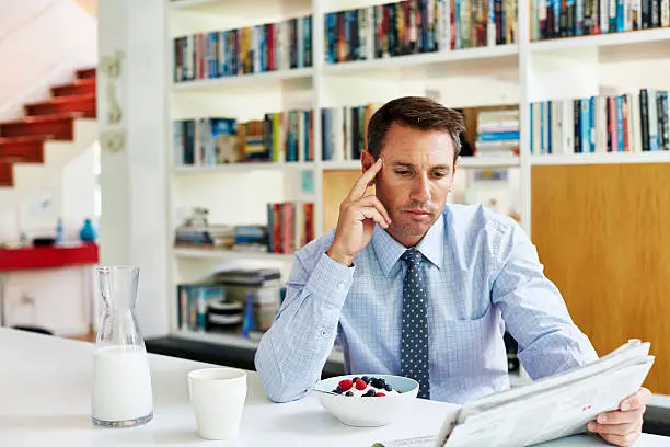 Mid adult businessman reading newspaper while having breakfast at home