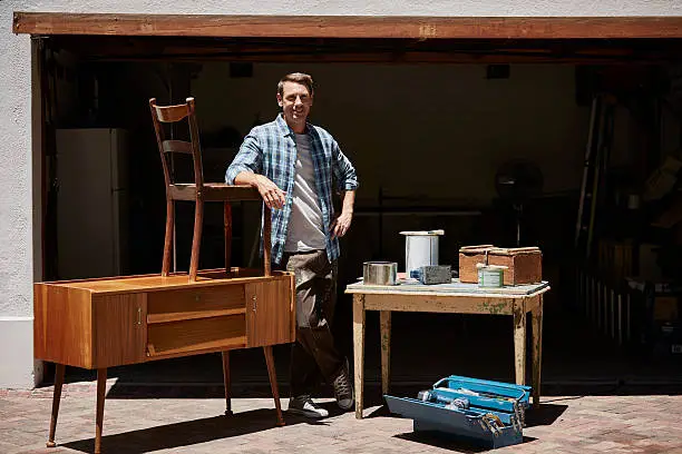 Full length portrait of happy mid adult man with furniture outside house