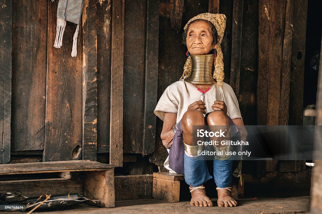 Traditional Padaung (Karen) woman from Myanmar Pan Pet, Myanmar - May 25, 2016: Portrait of Padaung (Karen) long neck woman in brass rings around their neck and traditional clothing near the house. Kayan tribe or Padaung are one of unique diverse ethnic minorities of east part of the country. Woman of the tribe are wearing a coil of brass rings around their necks from early age. Neck rings are very heavy. That is why collarbones and ribs goes down and starts deformation. There is  only visual  illusion of an elongated neck. For a long period of time Padaung people were persecuted by military regime over these visible tribal symbols. Some of them moved closer to the Thai border. But now situation has changed. The territory that  long time was restricted for tourist in Myanmar starts to be opened. Padaung Tribe Stock Photo