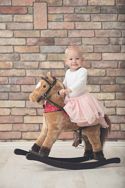 istock cute child playing with rocking horse 596769376
