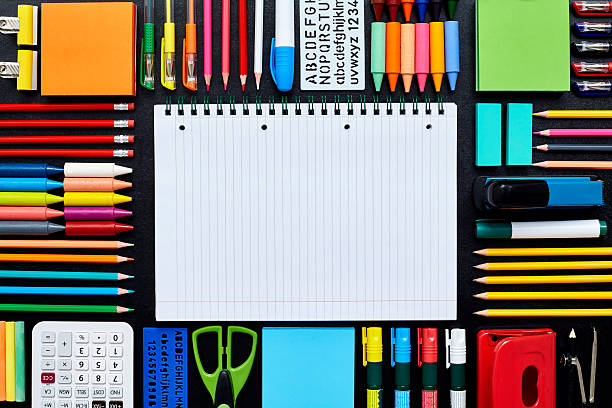 istock Spiral notebook surrounded by school supplies on blackboard 596770630