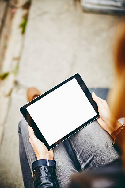 istock Young woman using tablet computer with blank screen outdoors 596771504