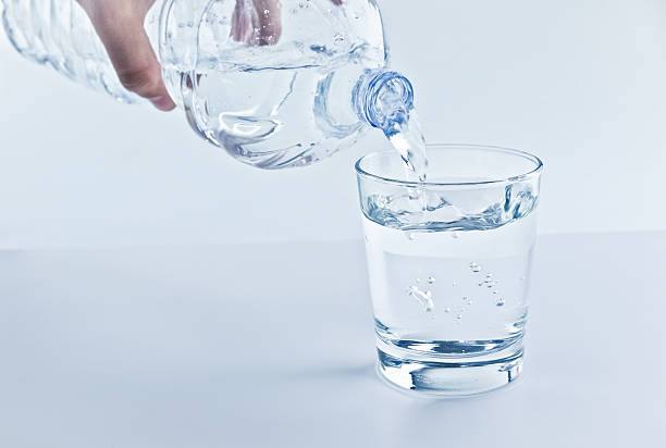 istock filling a glass with water through bottle, nutrition concept 596772364