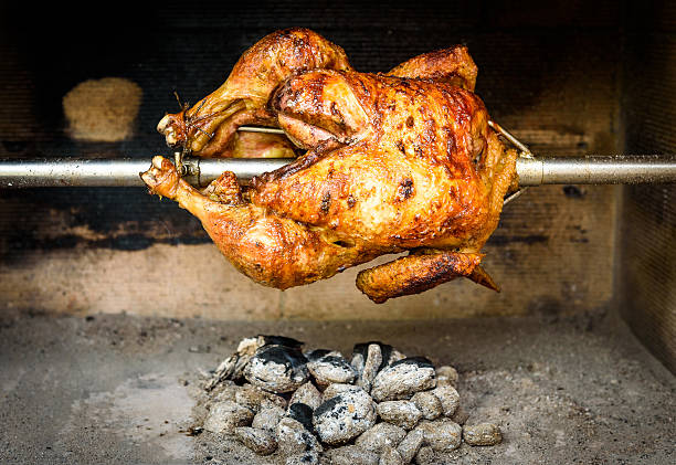 cucinare il pollo sul grill rotisserie con carbone e brique  - rotisserie chicken meat dinner foto e immagini stock