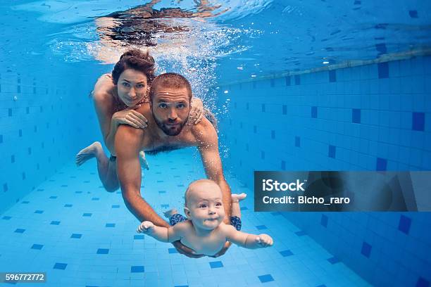 Family Fun In Swimming Pool Mother Father Baby Dive Underwater Stock Photo - Download Image Now