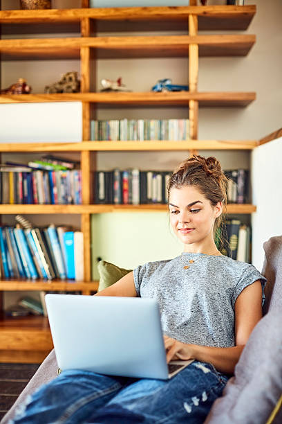 istock Beautiful young blogger using laptop on sofa at home 596773816