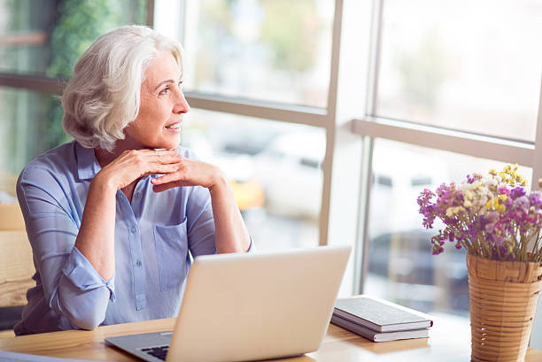 istock Pleasant delighted senior woman sitting at the table 596775616