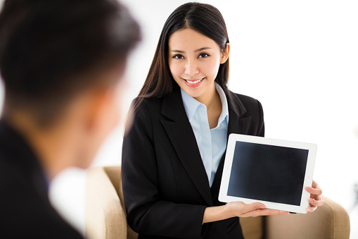Young business woman  showing blank tablet in office