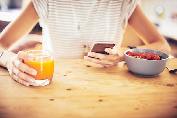 istock Woman with smart phone and orange juice at table 596779360