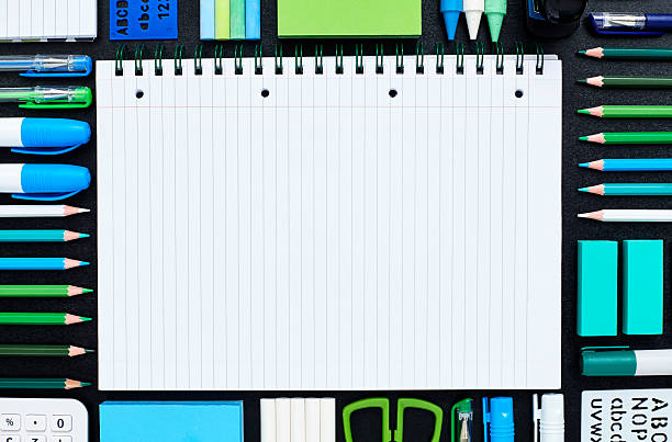 istock Spiral notebook surrounded by school supplies on blackboard 596779402